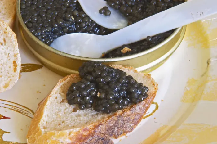 Framed Print : A tin of black caviar with slices of bread and a spoon of mother-of-pearl to scoop