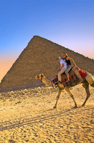 Tourists ride a camel in front of the Great Pyramids of Egypt in Cairo on the Giza