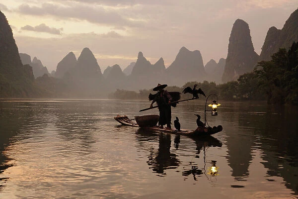 Traditional Chinese fisherman with cormorants on Li River at sunrise, near Guilin, China