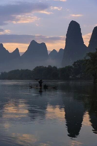 Traditional fisherman with his cormorants on the Li River at sunrise, Guilin, China