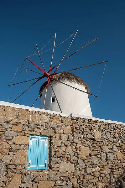 A traditional windmill set behind a rock masonry wall. Chora, Mykonos Island, Cyclades Islands, Greece