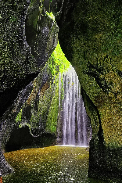 Tukad Cepung Waterfall in the central mountains of Bali, Indonesia. Carved through an underground canyon