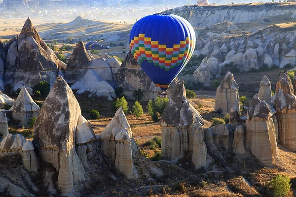 Turkey, Anatolia, Cappadocia, Goreme. Hot air balloon flying above  /  among rock formations