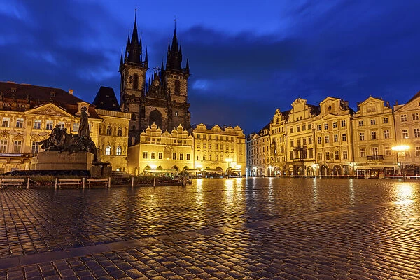 Tyn Church at dawn on wet cobblestones in Old Town Square in Prague, Czech Republic