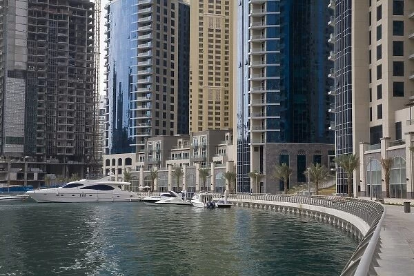 UAE, Dubai, Marina. Sidewalk along marina bay, with yacht and construction in background
