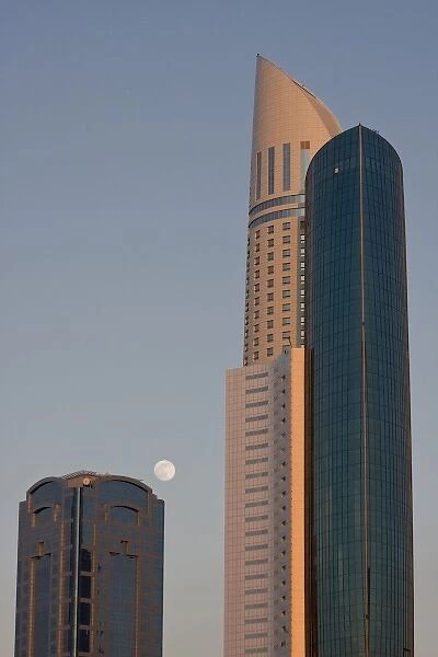 UAE, Dubai. Full moon rising between Park Place Tower and another building