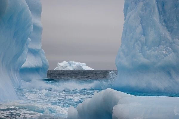 UK Territory, South Georgia Island. Blue-tinged icebergs frame a distant iceberg