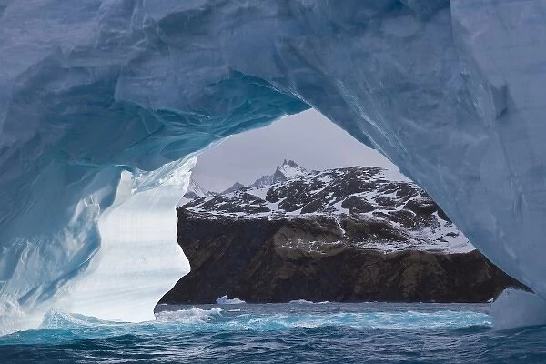 UK Territory, South Georgia Island, Iris Bay. Brown land framed by iceberg arch