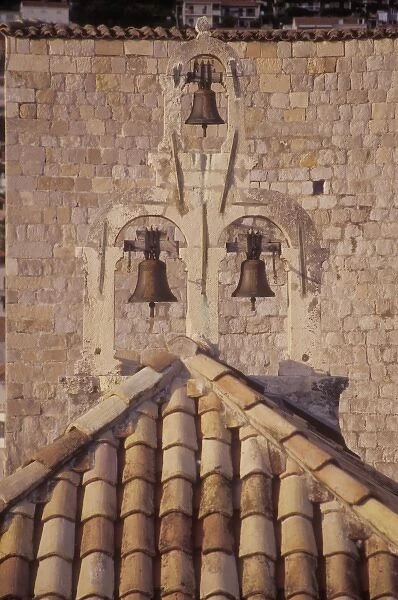 unknown. Small bells on a small church is lit by the late afternoon sun