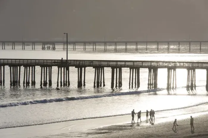 Framed Print : US, CA, Avila Beach. Silhouetted beach walkers approach pier end of day