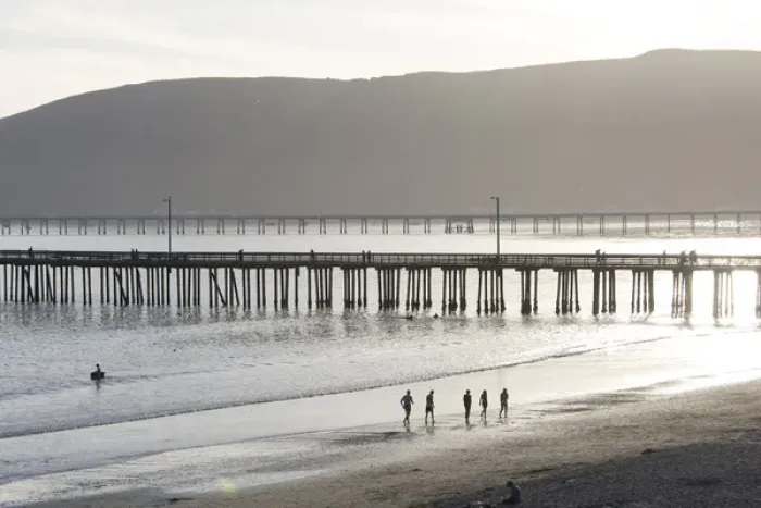 Framed Print : US, CA, Avila Beach. Silhouetted beach walkers approach pier end of day