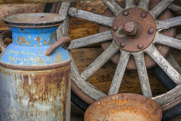 USA, Alaska. Antique milk can, wagon wheel and gold pan