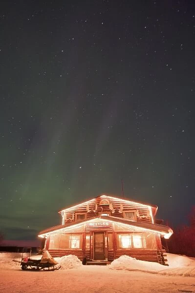 USA, Alaska, Bettles. The landmark Bettles Lodge lit beneath the northern lights