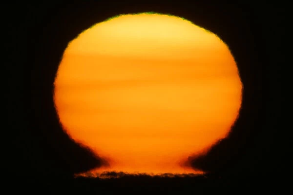 USA, Alaska, Homer. Sun at sunset distorts to look like a nuclear fireball. Credit as