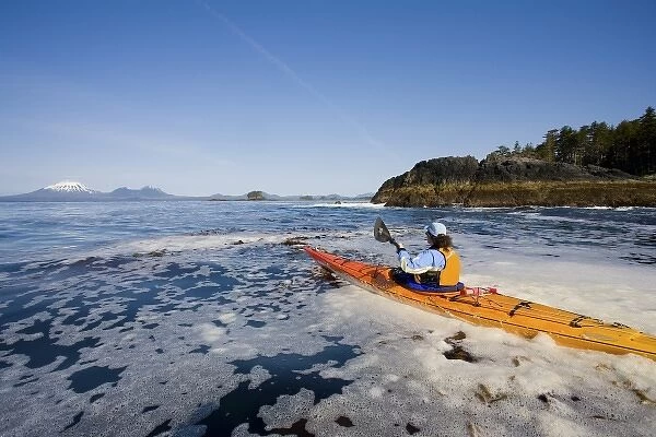 USA, Alaska, Sitka Sound. Woman sea kayaker on calm sea near Kruzof Island, Mt. Edgecumbe
