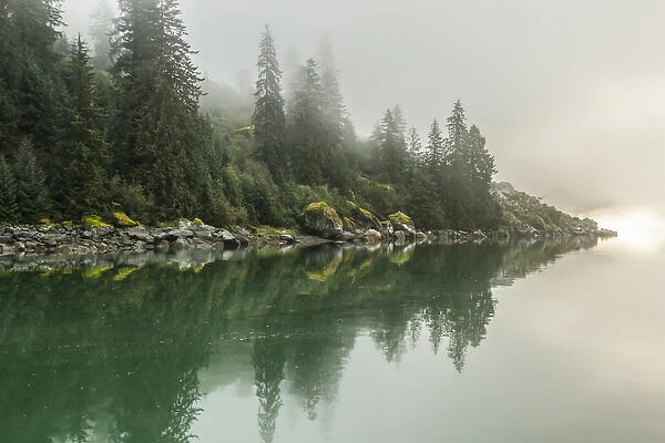 USA, Alaska, Tongass National Forest. Foggy shoreline and water reflection. Credit as