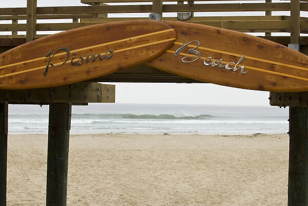 USA, CA, Pismo Beach. Vintage wooden surfboards frame entrance to inviting beach