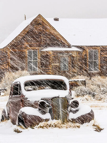 USA, California, Bodie. Abandoned car and building in snowfall