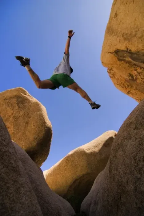 Framed Print : USA, California, Joshua Tree National Park. A male hiker leaps across a boulder. (MR)