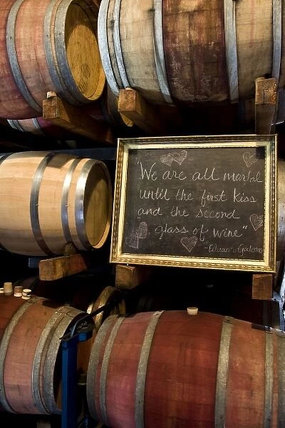 USA, California, Napa Valley. An Eduardo Galeano quote on a chalkboard among wooden barrels of wine
