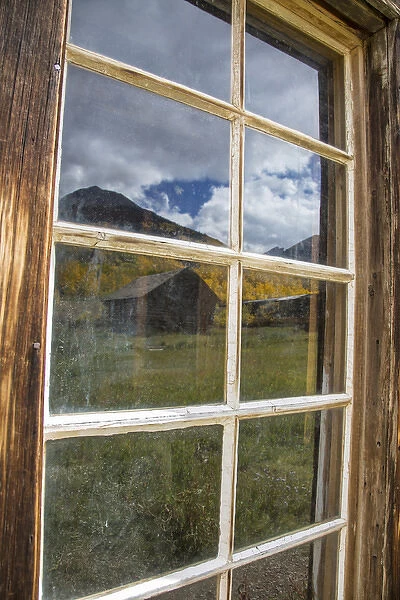 USA, Colorado, Ashcroft. Autumn scenic reflected in abandoned mining cabin window