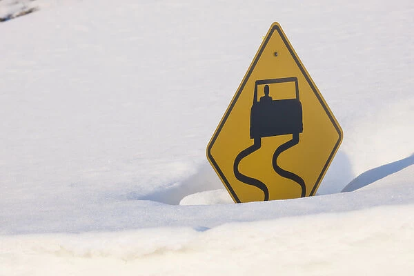 USA, Colorado. A slippery when wet sign buried in snow