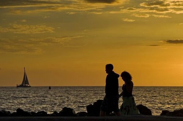 USA, Hawaii. A couple walks on the waterfront at sunset