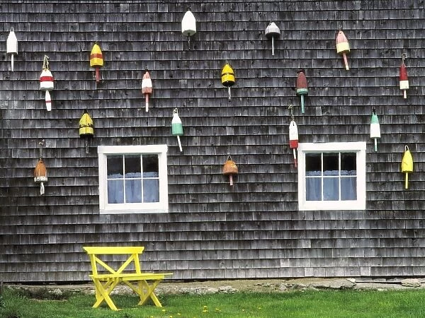 USA, Maine, Boothbay Harbor. Bright buoys decorate the weathered shingles of this