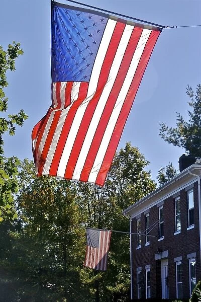 USA, Massachusetts, Lexington. Flags catch the sunlight over a brick home in Lexington