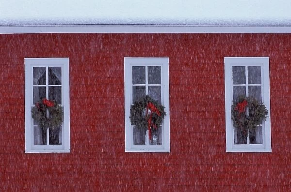 USA, Michigan, Three Christmas wreathes in schoolhouse windows during snowfall. Credit as