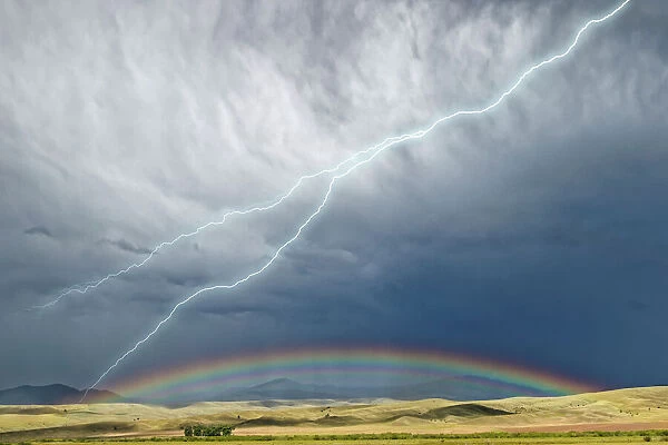 USA, Montana, Galen. Storm clouds with lightning and rainbow