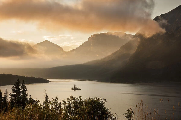 USA, Montana, Glacier National Park. Sunrise pierces clouds over St. Mary Lake. Credit as