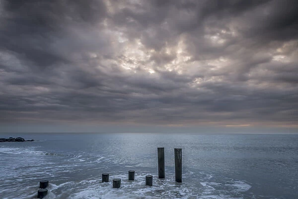 USA, New Jersey, Cape May National Seashore. Beach pilings on stormy sunrise. Credit as