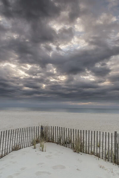 USA, New Jersey, Cape May National Seashore. Beach fence and stormy sunrise. Credit as