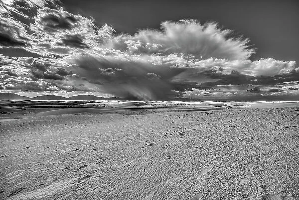 USA, New Mexico, White Sands National Park. Black and white of thunderstorm over desert and San Andres Mountains