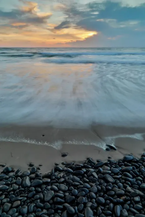 Framed Print : USA, Oregon, Arch Cape. Pacific coastline last evening light reflected in the sandy beach at low tide with foreground of shiny round black rocks