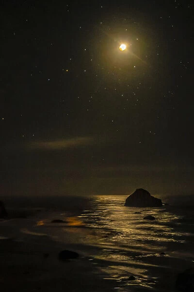 USA, Oregon, Bandon Beach. Lunar eclipse reflects on ocean shore at night