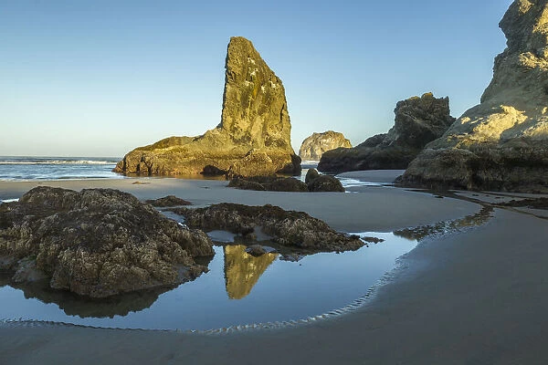 USA, Oregon, Bandon Beach. Rock formations and reflection in beach water