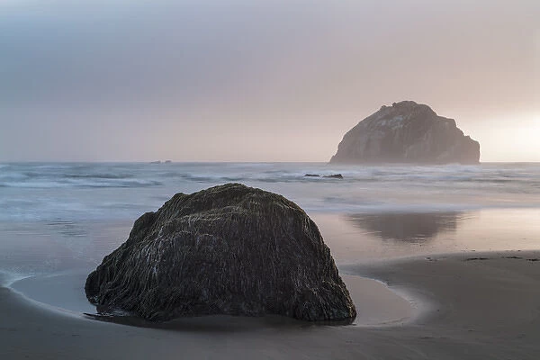 USA, Oregon. A boulder and sea stack at sunset