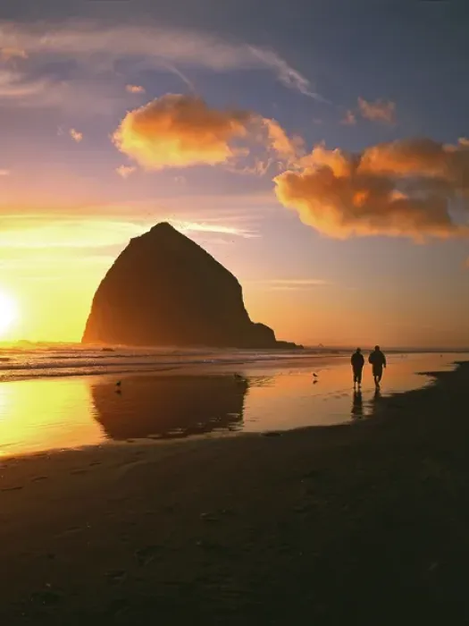 Framed Print : USA, Oregon, Cannon Beach. Couple walking beside Haystack Rock at sunset. Credit as