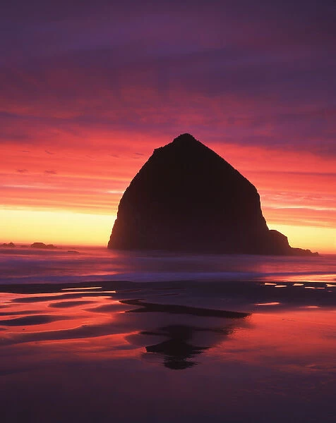 USA, Oregon, Cannon Beach, Haystack rock silhouetted on Cannon beach at sunset
