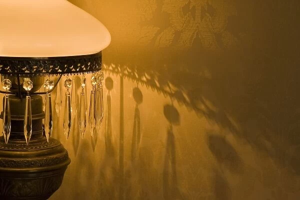 USA, Oregon, Cape Blanco. An antique lamp makes wall shadows in Hughes House at Cape