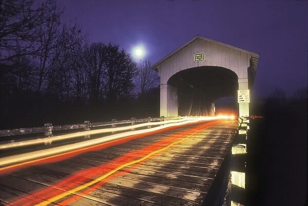 USA, Oregon. Car lights through Earnest covered bridge over Mohawk River at night with a full moon