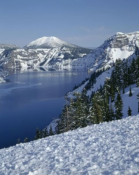 USA, Oregon, Crater Lake National Park. Evening light warms snowy rim of Crater Lake