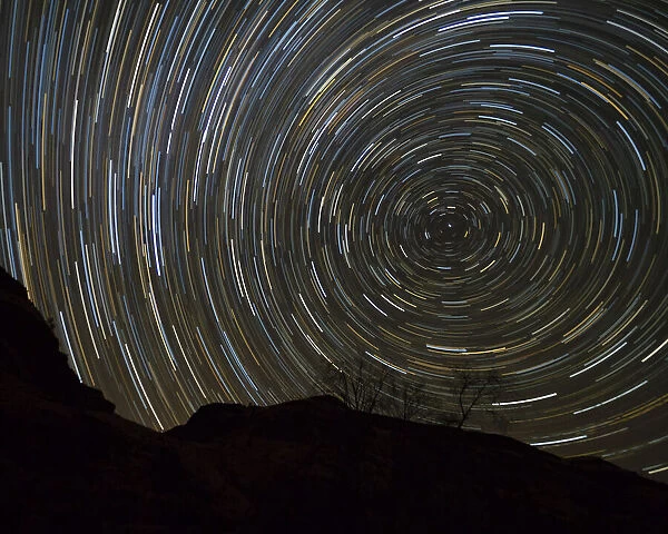 Usa, Oregon, Deschutes River. Circular star trails above cliff