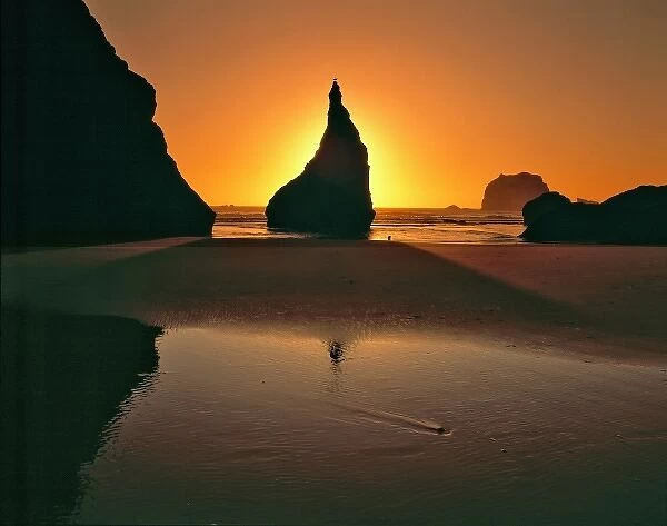 USA, Oregon, Face Rock Wayside. Sunlight bursts from behind a sea stack at sunset