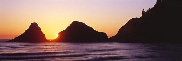 USA, Oregon, Heceta Head. The sun sets between two seastacks above Heceta Head Lighthouse