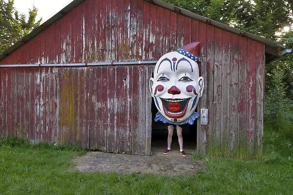 USA, Oregon, Oregon City. Person holding clown face in door of barn