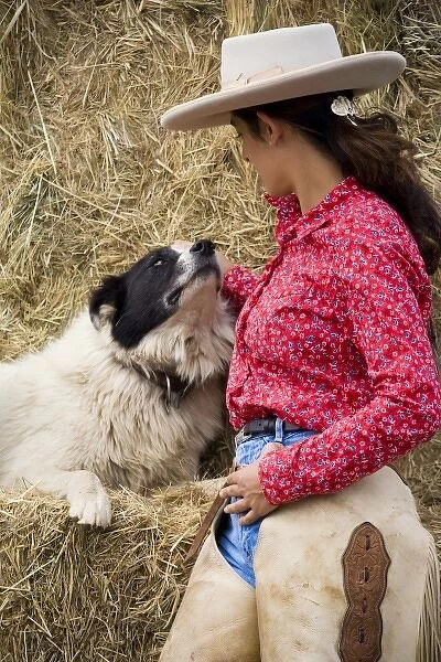 USA, Oregon, Seneca, Ponderosa Ranch. Profile portrait of a cowgirl petting her dog