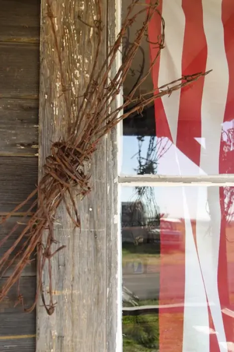 Framed Print : USA, Oregon, Shaniko. Flag in window next to coil of barbed wire. Credit as: Nancy